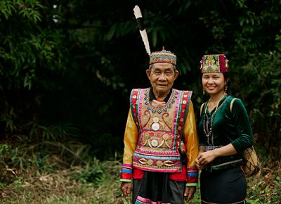  Two people standing in the forest smiling.