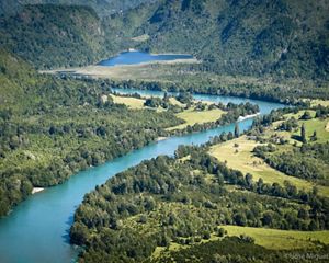 Aerial view of a blue river winding through densely forested lands and mountains.