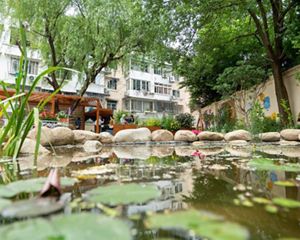Ground-level view across a small garden pond at volunteers working in a Hongxu Habitat Garden.