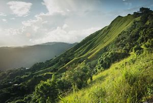 A cloudy sky frames a vibrant green mountainside.