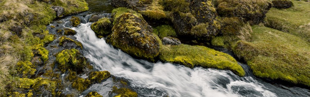 Waterfall cascading around mossy rocks.