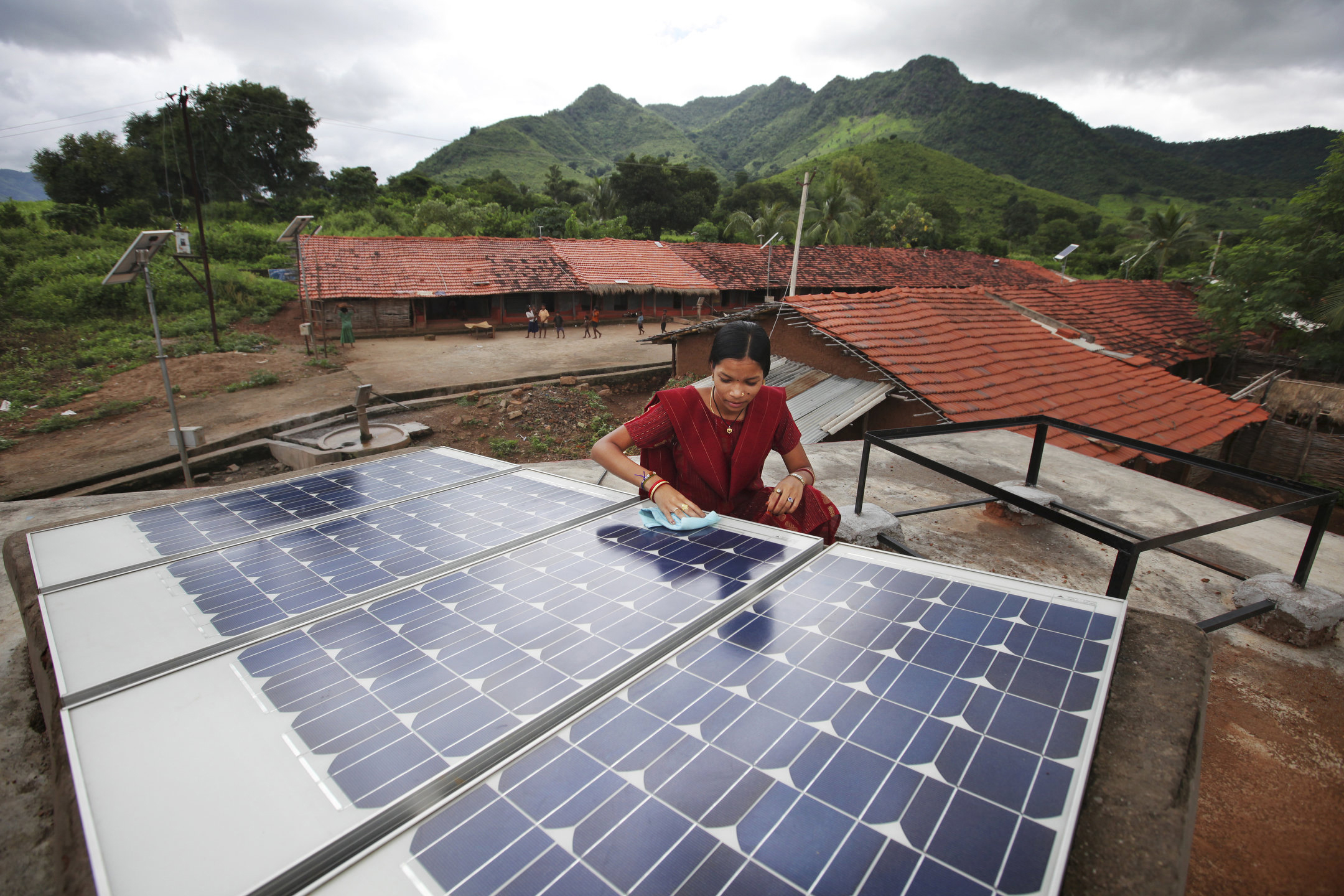 A woman wipes off solar panels in a village in India.