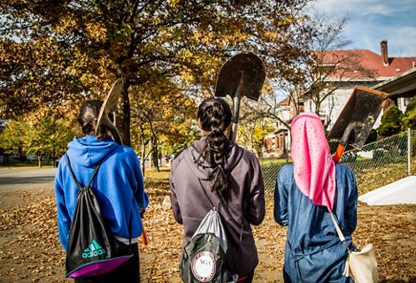Three young girls walk with garden tools