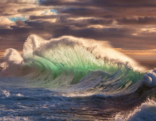 A massive wave breaks as the ocean swells towards the shore.