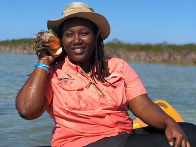 Trueranda Cox holds a conch up to her ear.